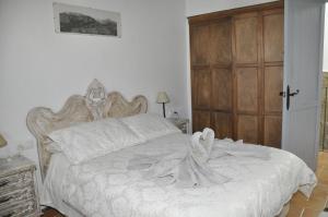 1 dormitorio con cama blanca y puerta de madera en Cassa Dulce, en Vejer de la Frontera