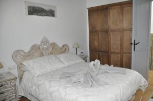 a bedroom with a white bed and a wooden door at Casa Dulce in Vejer de la Frontera