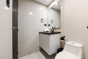 a white bathroom with a toilet and a sink at Sombras Modernas Apartment in Santa Cruz de la Sierra