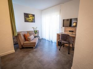 a living room with a couch and a desk and a television at Hotel- Restaurant Zum Schwan in Waldfischbach-Burgalben