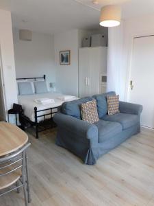 a living room with a blue couch and a bed at Modern bright studio apartment in south Glasgow in Glasgow