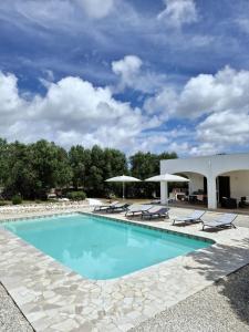 een zwembad met ligstoelen en parasols bij Trullo Tranquillo Ostuni in Ostuni