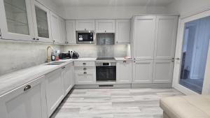 ボーンマスにあるA lovely 2 bedroom flat ideal for all occasionsの白いキッチン(白いキャビネット、電化製品付)