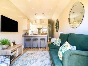 un salon avec un canapé vert et une cuisine dans l'établissement Raffinbow Retreat Cotswolds Cottage, à Mickleton