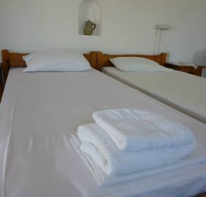 Duas toalhas brancas estão empilhadas numa cama branca em Marietta Studios Patmos em Skala