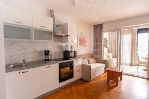 a kitchen with white cabinets and a living room at Apartment Anton in Baška
