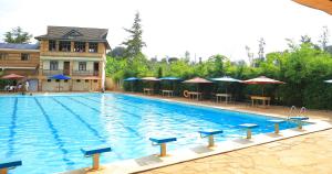 a large swimming pool with tables and umbrellas at Dancourt Funfair Hotel in Thika