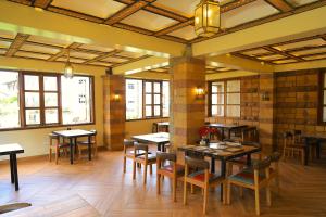 a dining room with tables and chairs and windows at Dancourt Funfair Hotel in Thika