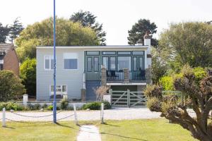 a house with a wrap around porch and glass at Historic Railway Home - Selsey Seafront in Selsey