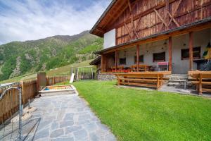 a building with wooden benches next to a grass yard at Schnatzhof Apartment Schwalbennest in Naturno