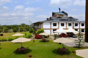 a large building with tables and umbrellas in front of it at Dancourt Funfair Hotel in Thika
