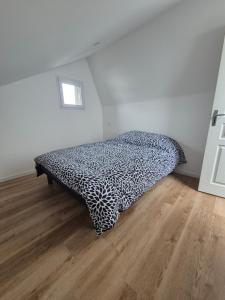 Una cama en blanco y negro en una habitación con suelo de madera. en Gite de l'usine, en Roussay