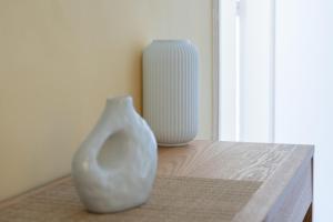 two white vases sitting on a table next to a window at The Psyri Collection in Athens +52 photos