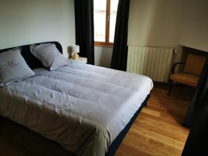 a bed in a bedroom with a chair and a window at La Maison d'Hortense au coeur du vignoble in Saint-Bris-le-Vineux