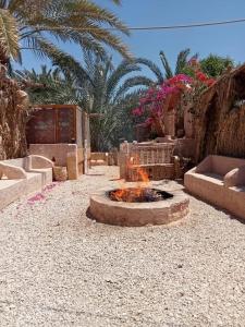 un braciere in un cortile di ghiaia con palme di Siwa Gardenia Cottage اكواخ سيوة جاردينيا a Siwa