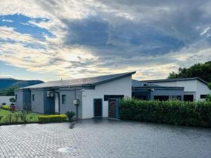 a white house with a driveway in front of it at Pula Nala Lodge Bed & Breakfast in Rustenburg
