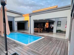 a house with a swimming pool and a wooden deck at Pula Nala Lodge in Rustenburg