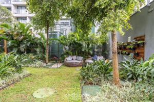 ein Garten mit einer Couch und Bäumen und einem Gebäude in der Unterkunft Studio Moderno a 450m do Metrô – ISM0806 in São Paulo