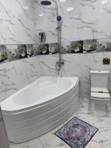 a white bathroom with a tub and a toilet at Art Apart Residence in Tashkent +24 photos