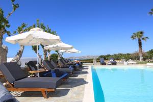 a group of chairs and umbrellas next to a swimming pool at Fragoulis Village in Parasporos