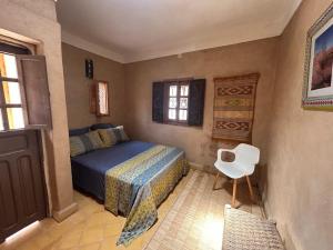 a bedroom with a bed and a white chair at Riad Dar Laure in Taroudant +63 photos