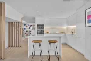 a kitchen with white cabinets and bar stools at Townhouse Eden Golf Chaparral in Málaga