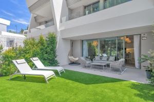 a patio with white chairs and a green lawn at Townhouse Eden Golf Chaparral in Málaga
