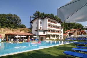 a large swimming pool with chairs and a building at Студио в курорт Шкорпиловци in Shkorpilovtsi