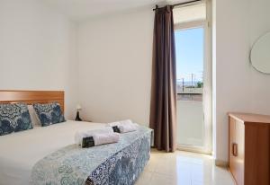 a bedroom with a bed and a large window at Apartments MTB Only Couples in Lloret de Mar
