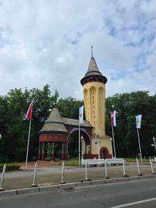 a building with a tower on the side of a road at Apartman Marjanović Palić in Palić +52 photos