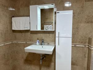 a bathroom with a sink and a mirror and a refrigerator at Apartments Carpe Del Mare Complex Carpe Diem Balchik in Balchik