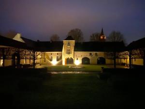 a large building with a clock tower at night at Le Colombier d'Orbais in Perwez