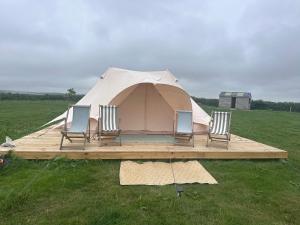 a tent with four chairs in a field at Springfield glamping in Marwood