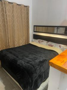 a bed with a black blanket on top of it at Aconchego in Pelotas +3 photos