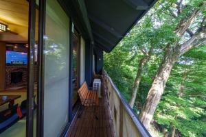 a balcony of a house with a large tree at Y'sINN 宮城野 040H in Hakone