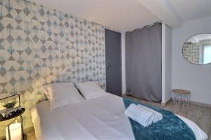 a bedroom with a white bed and a wall at Les Apparts du Pont Vert - lit double - WiFi - tout inclus - 2 in Troyes +11 photos