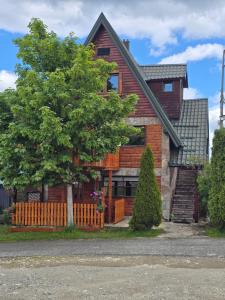 a house with a wooden fence and a tree at Holiday Home Vile Calimero in Žabljak