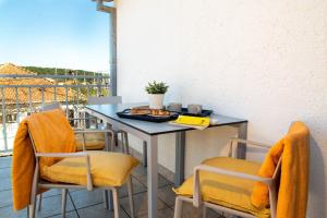 une table et des chaises avec une assiette de nourriture dans l'établissement Quirky Penthouse Apartment, à Vrboska