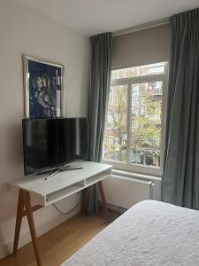 a bedroom with a desk with a tv and a window at Great Apartment Amsterdam in Amsterdam