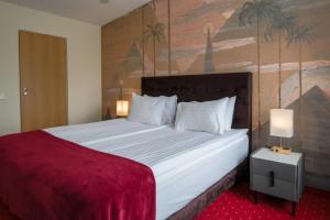 a bedroom with a large white bed with a painting on the wall at Agneta Apartamentai in Druskininkai
