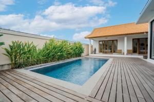 una piscina con terraza de madera junto a una casa en The Buddha Villa by Homely Bali, en Kerobokan