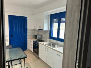 a kitchen with white cabinets and a blue door at Smaragda's Studio in Kithnos