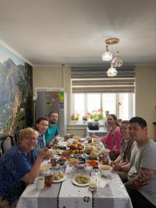 a group of people sitting around a table eating food at Guest House Ayara in Kyzyl-Tuu