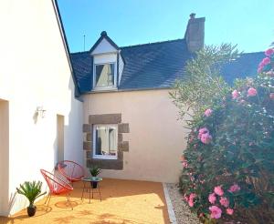 ein Haus mit zwei Stühlen, einem Fenster und Blumen in der Unterkunft Belle maison avec jardin clos proche plage à l'ILE GRANDE - Réf 291 in Pleumeur-Bodou