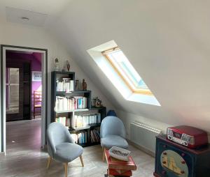 ein Dachzimmer mit zwei Stühlen und einem Bücherregal in der Unterkunft Belle maison avec jardin clos proche plage à l'ILE GRANDE - Réf 291 in Pleumeur-Bodou