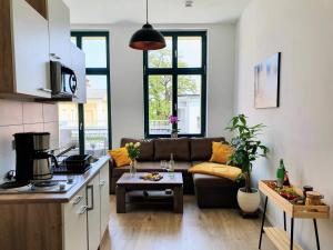 ブランデンブルク・アン・デア・ハーフェルにあるHogulu - 2 - RAUM - App 23 mit Balkon im Herzen der Altstadtのソファとテーブルのあるキッチンとリビングルーム