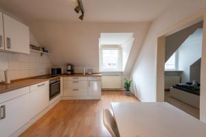 eine Küche mit weißen Schränken und einem Tisch in der Unterkunft HagenStay Mittelstadt 1 in Hagen + 6 Fotos
