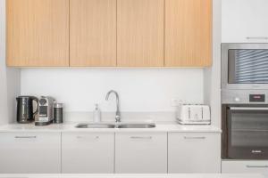 グランベにあるSealodge - Luxury Apartment on the Coastの白いキャビネットとシンクと電子レンジを備えたキッチン