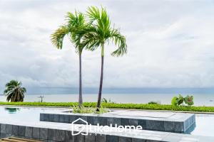 a swimming pool with palm trees and the ocean at Unity Cabo Branco - LikeHome Hospedagens in João Pessoa