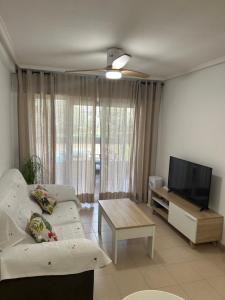 ein Wohnzimmer mit einem weißen Sofa und einem Flachbildfernseher in der Unterkunft Descanso y jardines con piscinas in Arenales del Sol